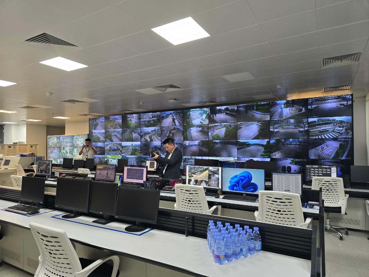 Los Angeles transit control room: a video wall, desks and empty chairs, two visitors