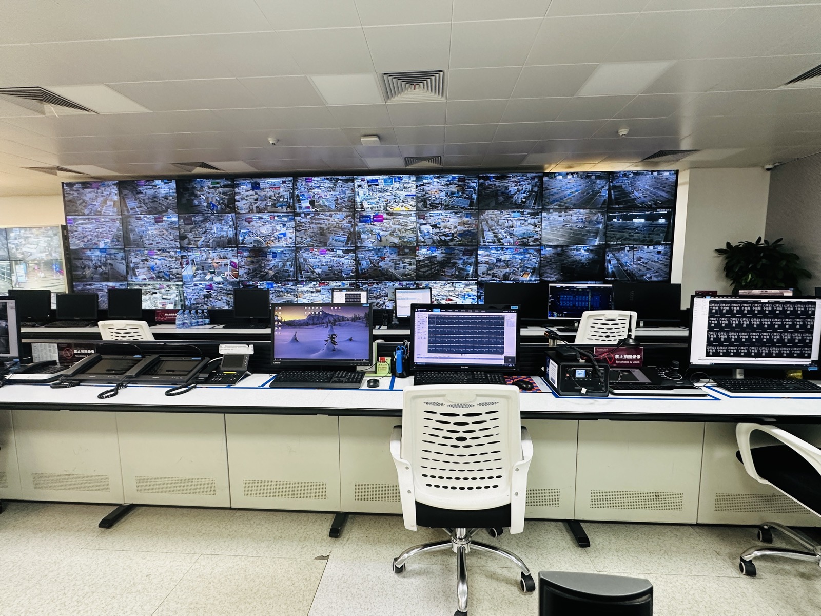 A control room in Shenzhen: a wall of CCTV feeds above a row of empty chairs